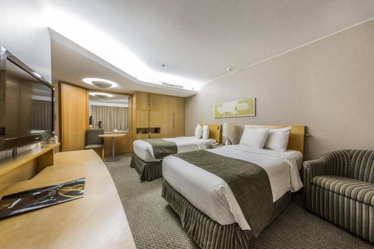 Habitación de hotel con dos camas, un escritorio, un televisor y un sofá.