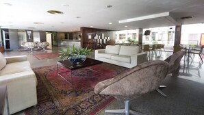 Un salon moderne avec un canapé, un fauteuil, une table basse et une grande fenêtre.