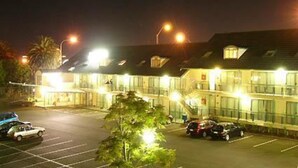 Un hotel con varios espacios de estacionamiento y un exterior bien iluminado.