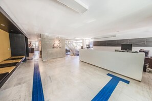Un moderno vestíbulo de hotel con mostrador de recepción, una escalera y una vista despejada del interior.