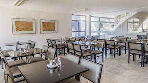 A modern hotel dining area with multiple tables and chairs, large windows, and a staircase. - Bittar Inn Hotel (Brasília)