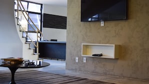 A modern interior with a staircase, a flat-screen TV mounted on the wall, and a small shelf. - Bittar Inn Hotel (Brasília)