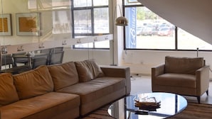 A modern interior with a leather sofa, a round glass coffee table, and a beige armchair. - Bittar Inn Hotel (Brasília)
