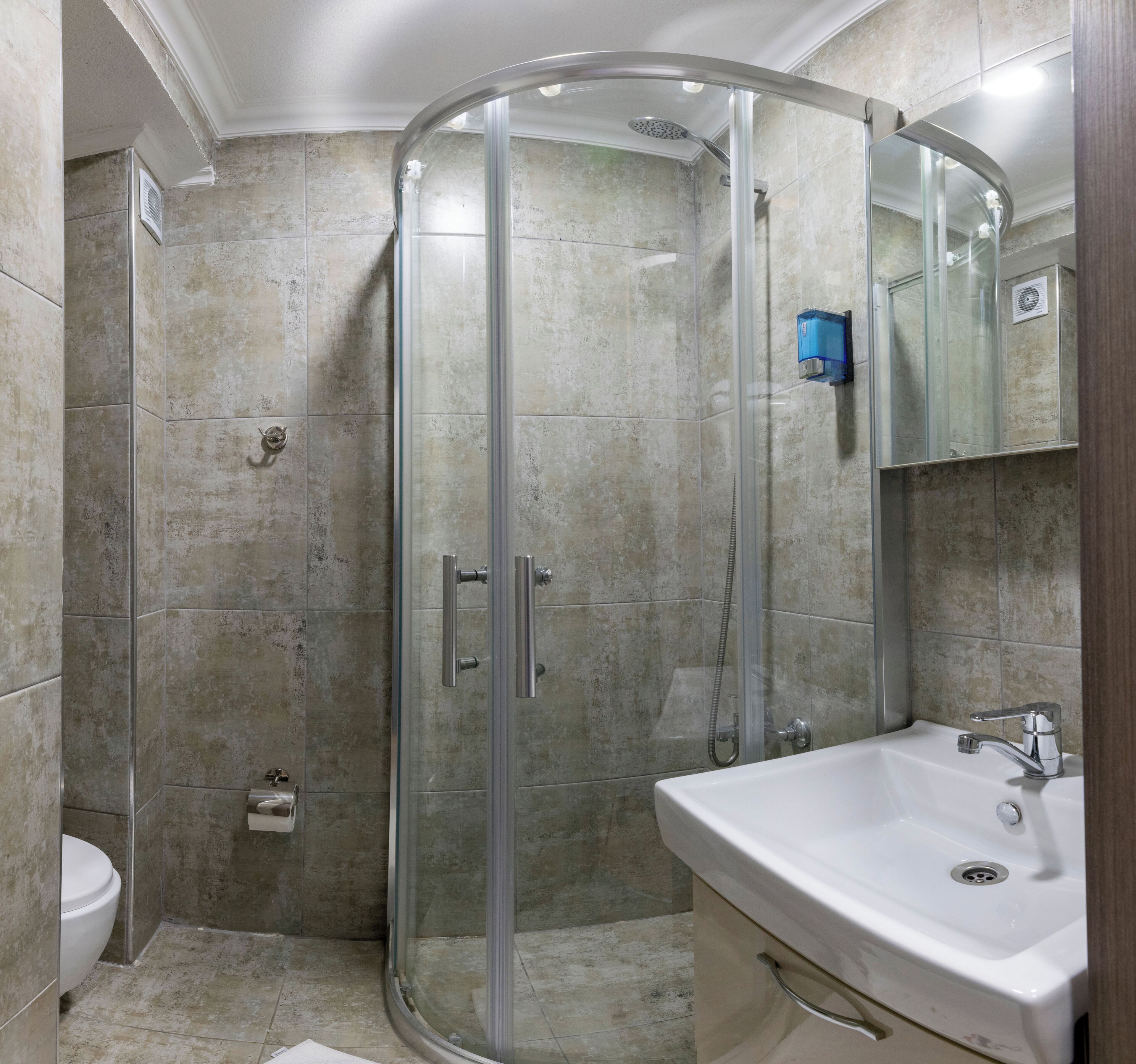 Un baño con ducha de mampara de vidrio, lavamanos y espejo.