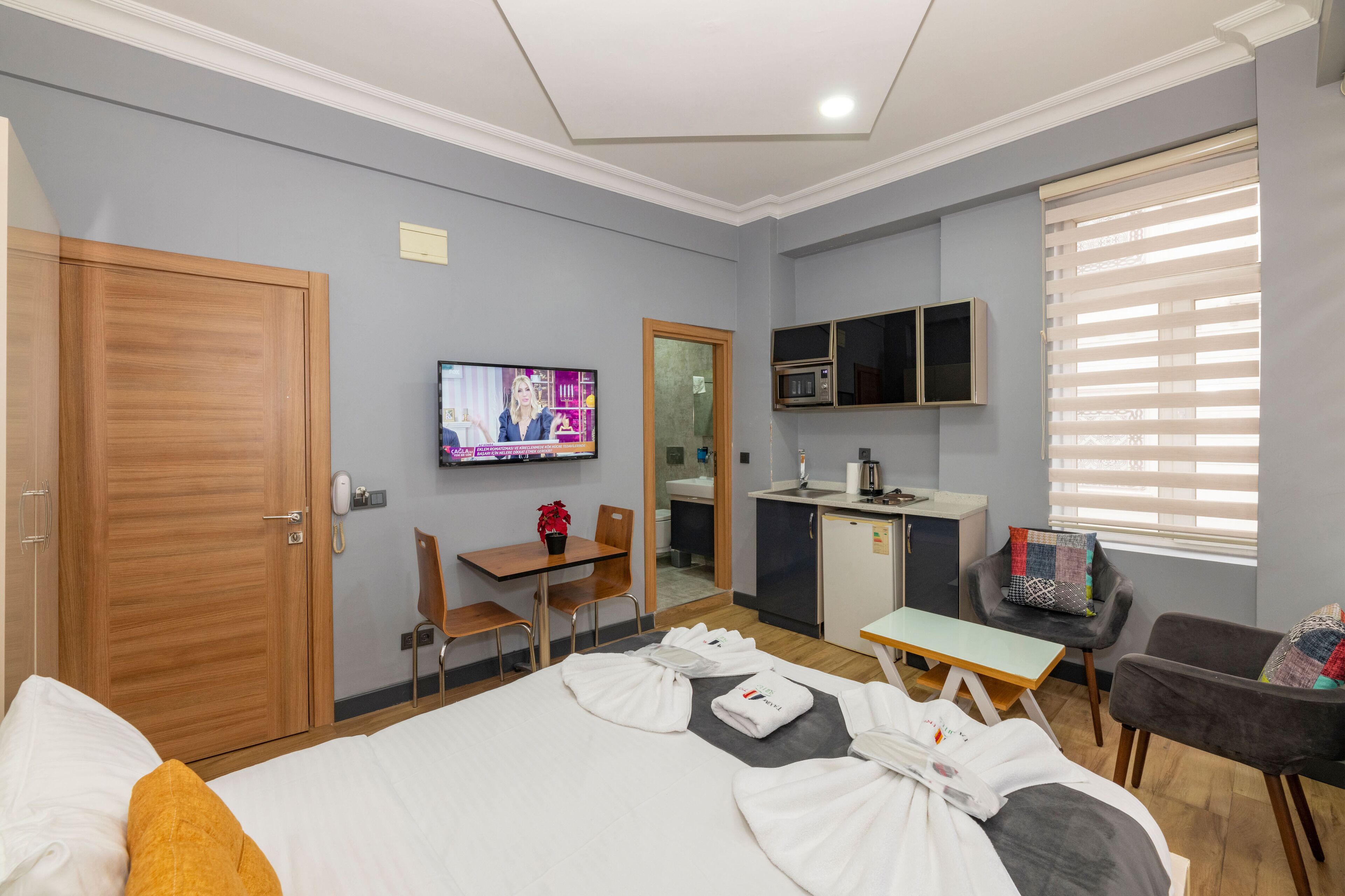 Ein Hotelzimmer mit einem Bett, einem Schreibtisch, einem Fernseher, einer Küchenzeile und einer Sitzecke.