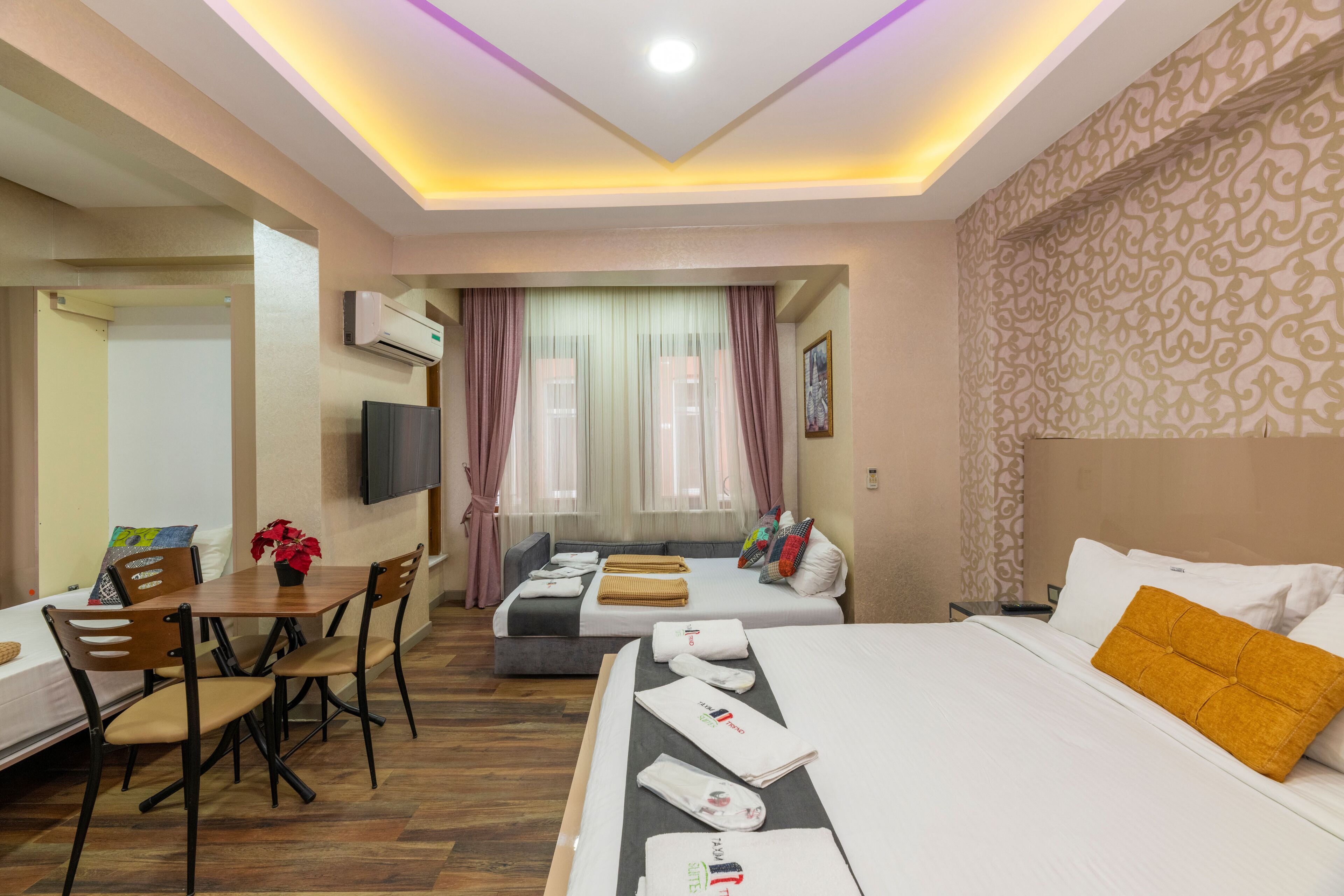 Een hotelkamer met een bed, een bank, een eettafel met stoelen en een televisie.