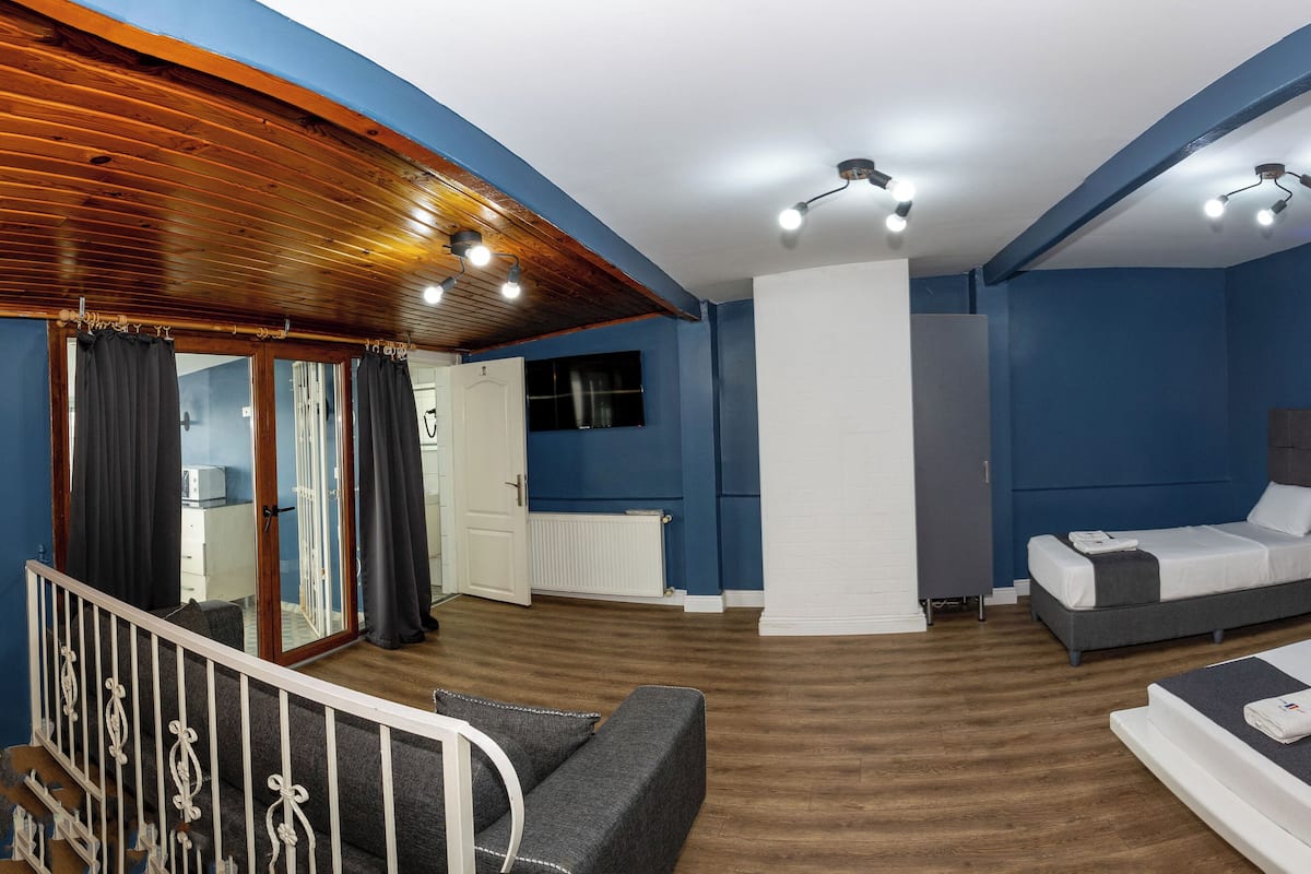 A hotel room with a bed, a desk, and a staircase.