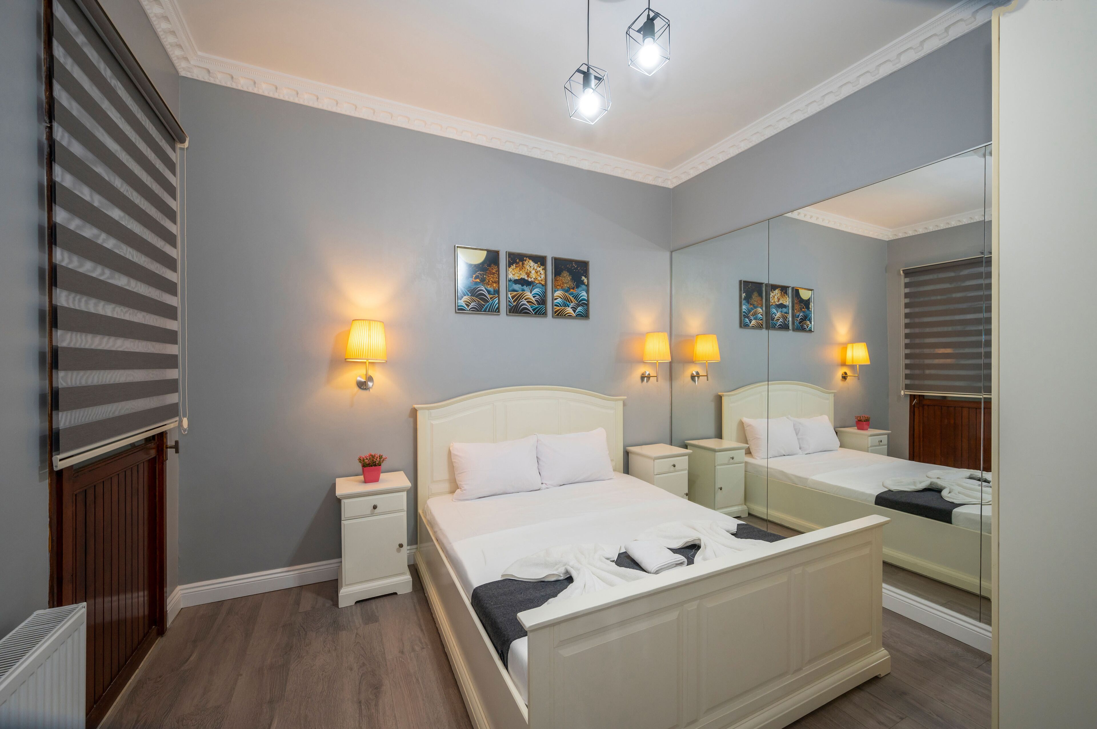 Een hotelkamer met een groot bed, nachtkastjes, een spiegel en kunst aan de muur.