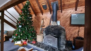 A cozy room with a Christmas tree, a stone fireplace, skis, and a television mounted on the wall.