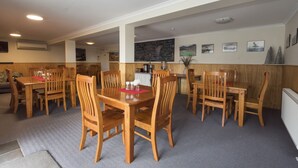 A dining area with wooden tables and chairs, a chalkboard menu, and framed pictures on the wall.