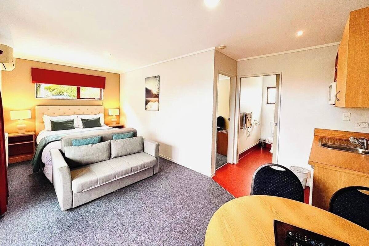 Habitación de hotel con cama, sofá, escritorio y kitchenette.