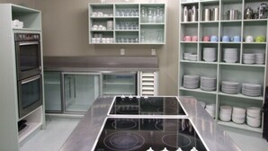 Een moderne keuken met een centraal eiland, een inbouwoven en kastjes met glazen deurtjes.