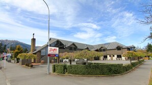 Drifters Inn in moderne architectuur, met een opvallende schoorsteen, grote ramen en een aangelegde voortuin met een haag en een grote rots.
