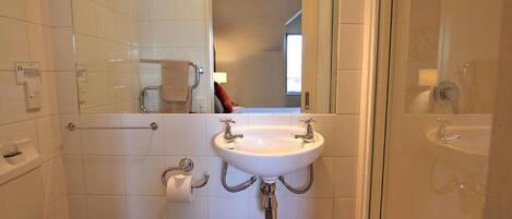 Un baño con un lavamanos blanco, un inodoro y una zona de ducha.