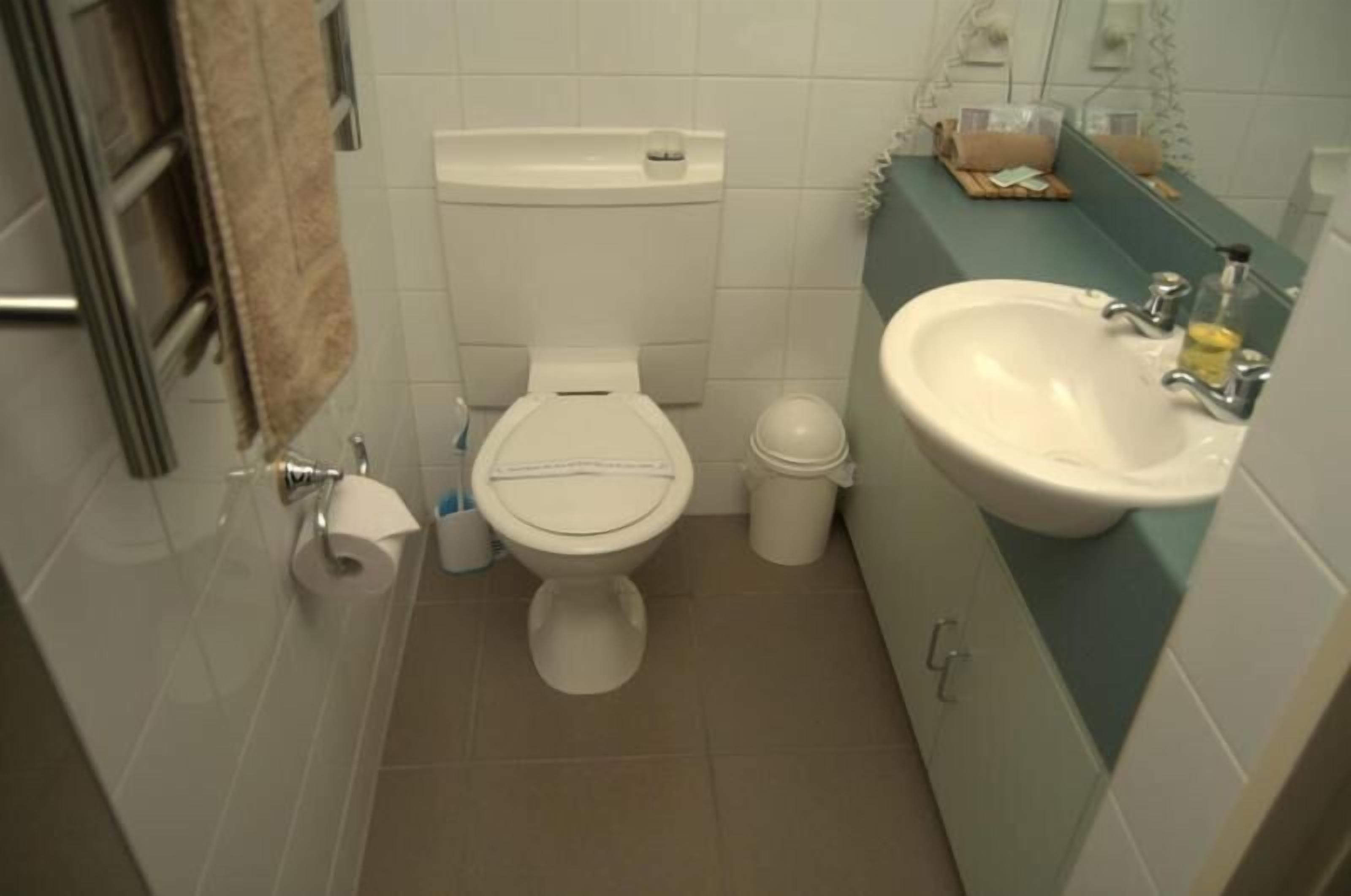 Un baño pequeño con inodoro, lavamanos y espejo.