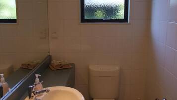 Un baño con un lavamanos blanco, un inodoro y una ventana sobre el inodoro.
