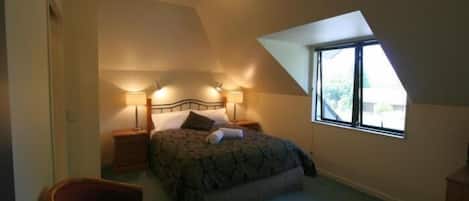 Une chambre à coucher avec un lit, deux tables de chevet, une chaise et une fenêtre.