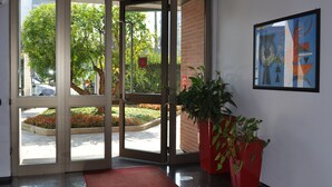 A hotel entrance with a glass door, a red mat, and a potted plant. - Residence Le Corti (Milan)