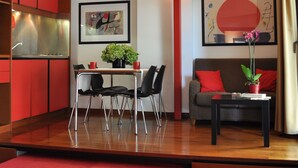 A modern living room with a dining area, red furniture, and artwork on the walls. - Residence Le Corti (Milan)