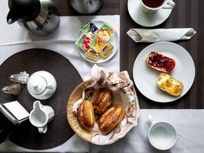 Desayuno con pan, mermelada, mantequilla y café.