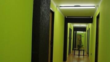 Un pasillo con paredes verdes y suelo de madera, que conduce a una puerta al final.