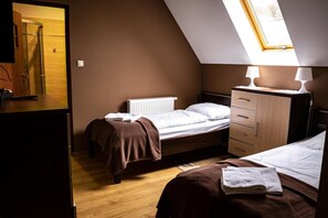 Un dormitorio con dos camas, un aparador de madera, un radiador y un tragaluz.