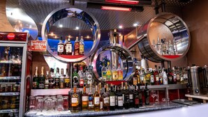 Een bar met verschillende drankflessen, glazen en een Coca-Cola koelkast.
