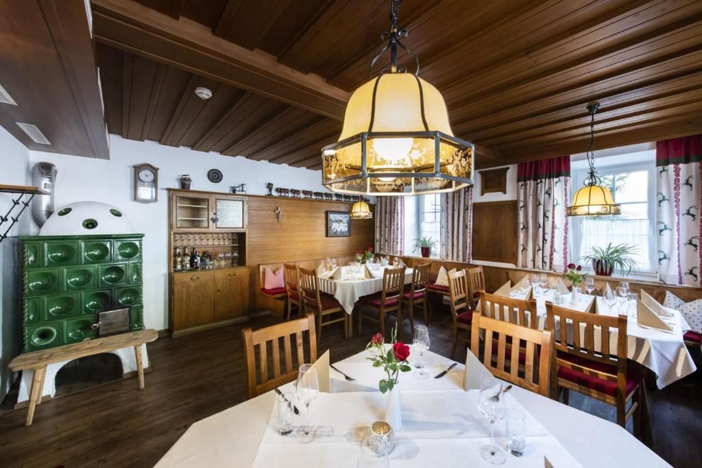 Un restaurante con vigas de madera en el techo, un armario verde y mesas dispuestas para comer.