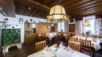 Un restaurante con vigas de madera en el techo, un armario verde y mesas dispuestas para comer.