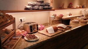 Buffet de petit esmorzar amb diferents tipus de pa, pastissos i una torradora.
