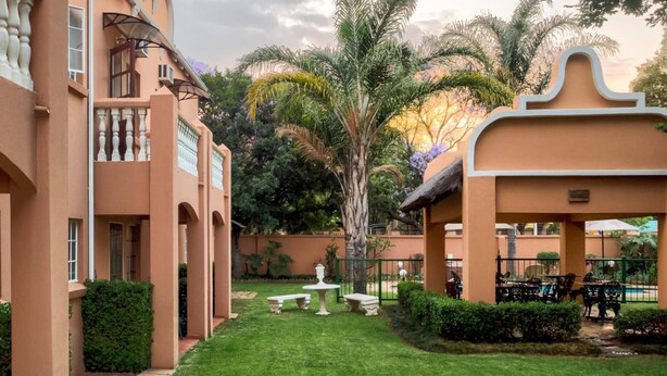 Un patio con una palmera, un porche y una zona de piscina.