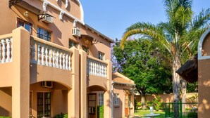 Un edificio de dos pisos con fachada simétrica, un patio cubierto y un césped bien cuidado.