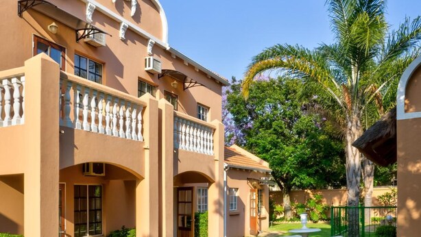 A two-story building with a symmetrical facade, a covered patio area, and a well-maintained lawn.