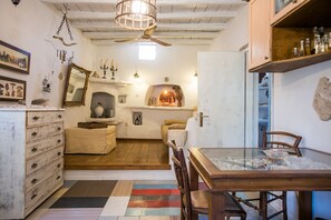 A rustic kitchen with a wooden ceiling, a dining table with chairs, and a variety of kitchen utensils and decorations on the walls. - Anthippi Guest House (Paros)