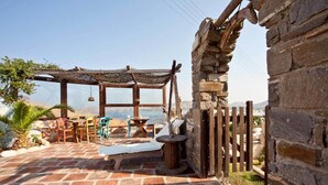 A stone patio with outdoor seating, a pergola, and a stone wall.