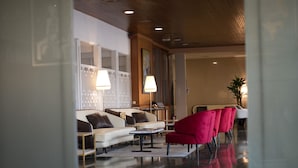 A modern lobby with a white sofa, red chairs, and a glass coffee table. - Hotel Reconquista (Alcoy)