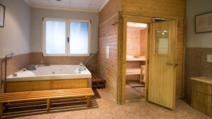 A wooden spa room with a large bathtub, wooden benches, and a sauna entrance. - Hotel Reconquista (Alcoy)