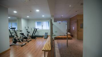 Et fitnessrum med træningsudstyr, en træbænk og en murstensgulv.