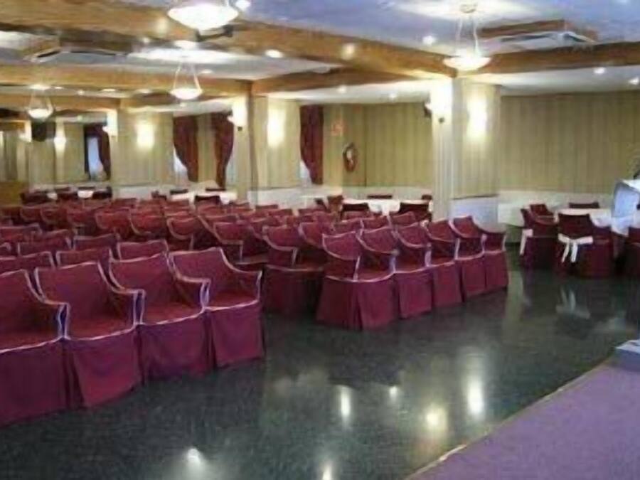 Un salón de conferencias con filas de sillas, un atril y suelo alfombrado.