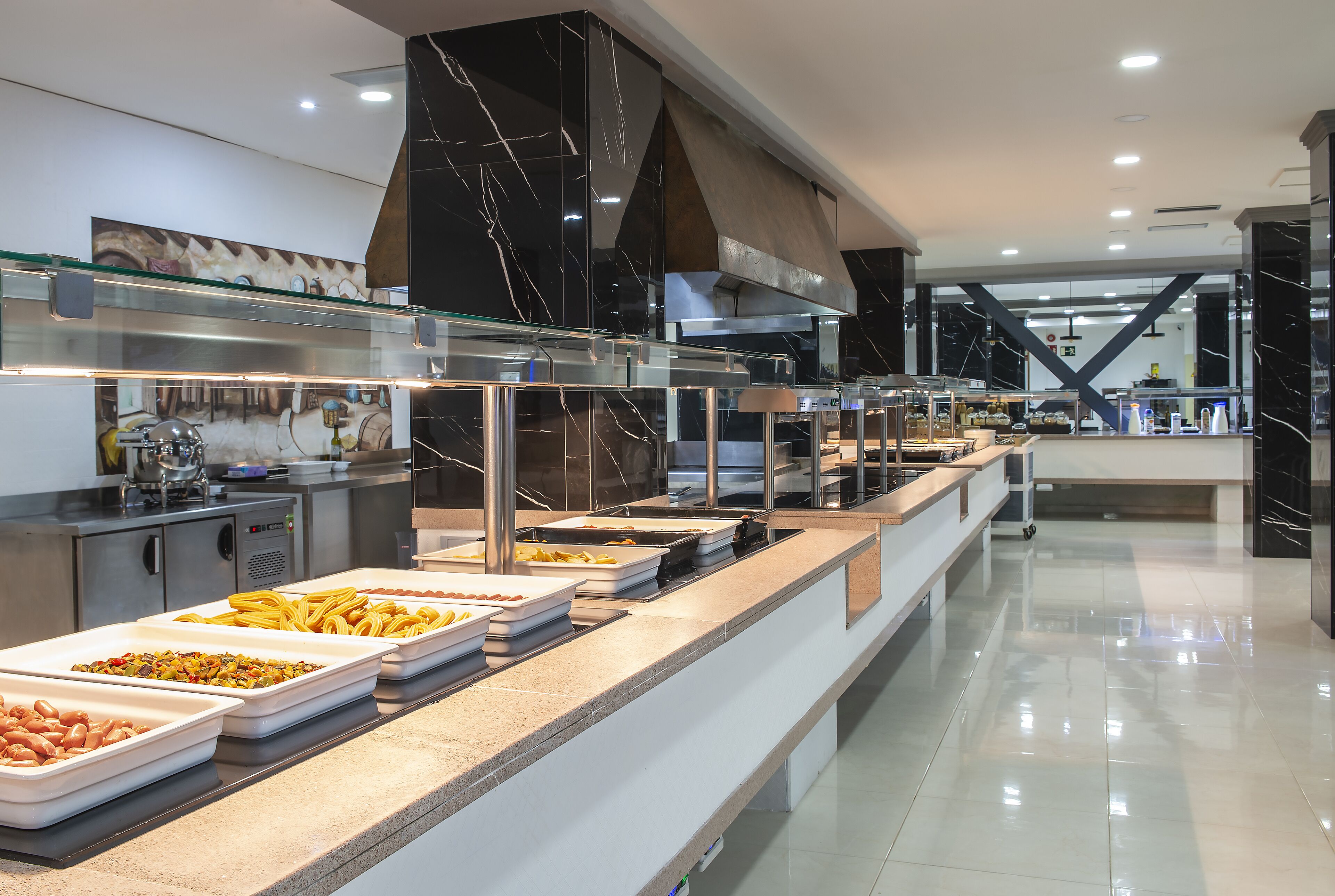 A buffet area with various food options and a modern kitchen in the background.