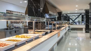 Un espace buffet proposant une variété de plats, avec une cuisine moderne en arrière-plan.