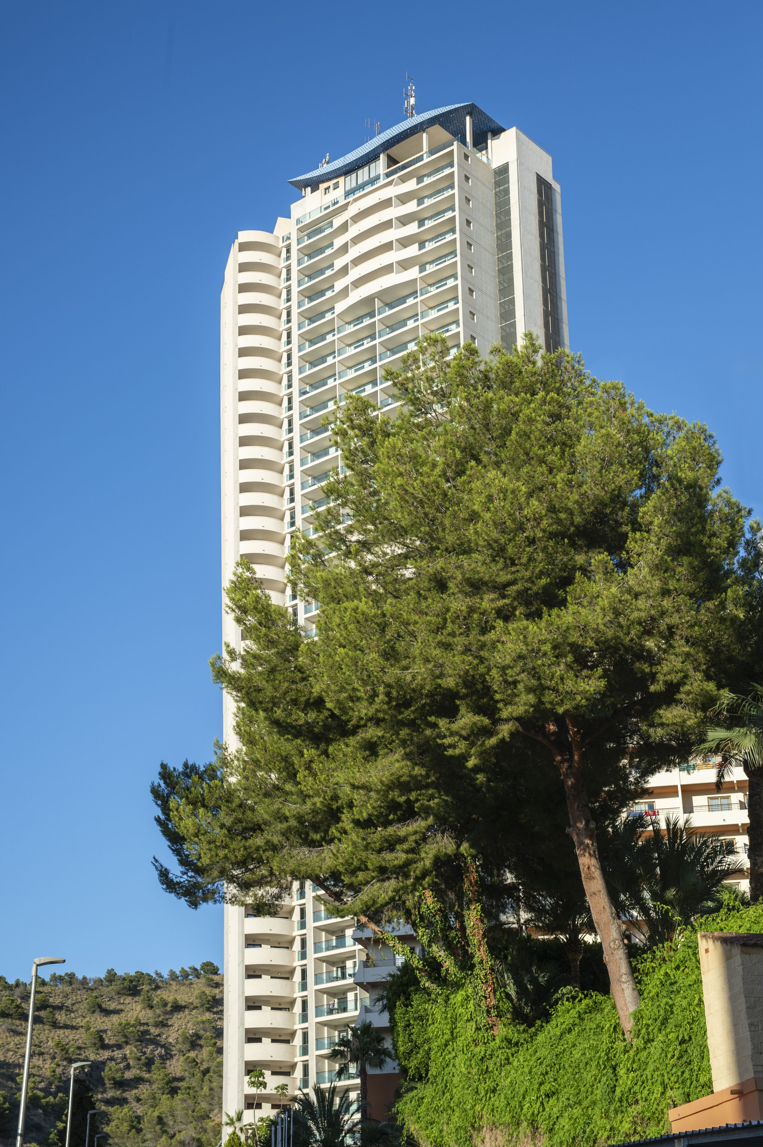 Un edificio alto y moderno con varios balcones y techo plano.