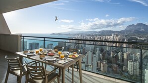 A dining area with a table set for breakfast, overlooking a cityscape and mountains. - Pierre & Vacances Benidorm Horizon (Benidorm)