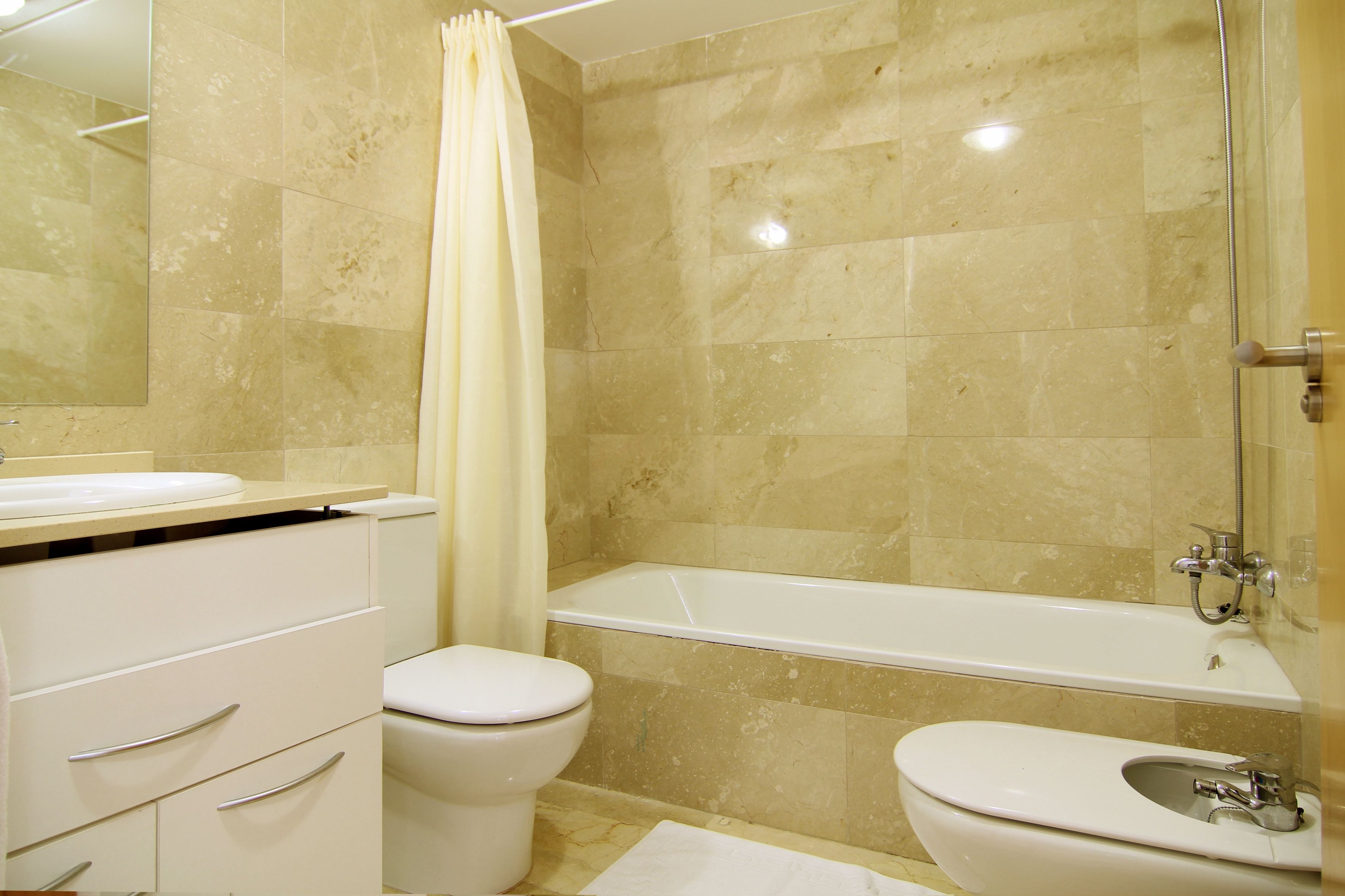 A bathroom with a bathtub, a toilet, and a bidet.