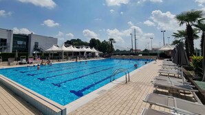 A swimming pool with tiled deck, lounge chairs, and umbrellas. - Green Garden Resort (Mestre)