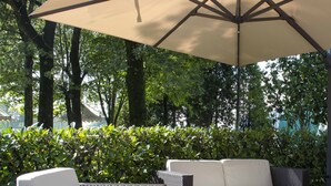 An outdoor seating area with wicker furniture and a large umbrella. - Green Garden Resort (Mestre)