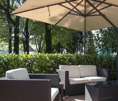 An outdoor seating area with wicker furniture and a large umbrella.