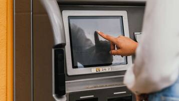 A person using an ATM machine with a blue sign above it.