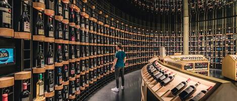 A wine cellar with numerous bottles arranged on shelves and a tasting area.