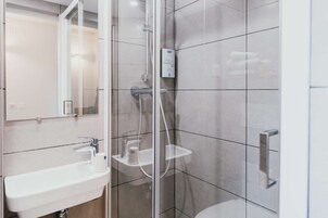 Un baño moderno con ducha envuelta en vidrio, lavamanos con espejo e inodoro.